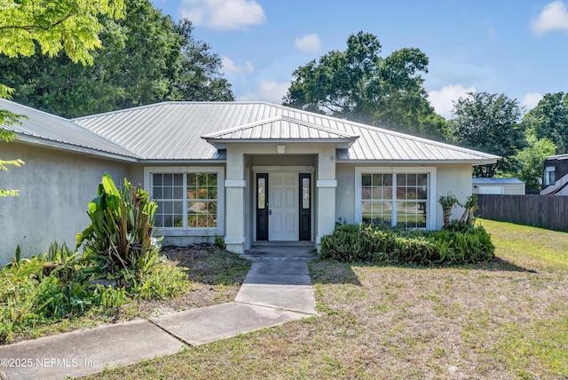 5329 Ogilvie Ln, Saint Augustine, FL 32086 - view of front of property featuring stucco siding, fence, a front yard, and metal roof