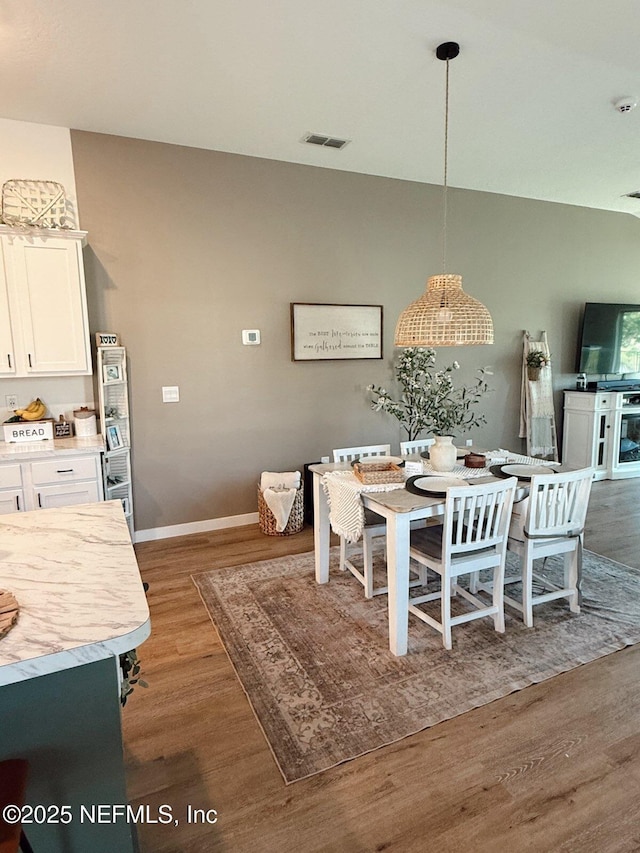 dining area with visible vents, wood finished floors, and baseboards
