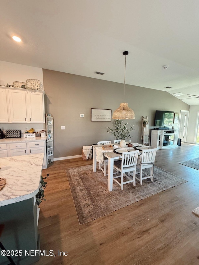 dining space with lofted ceiling, visible vents, wood finished floors, and baseboards