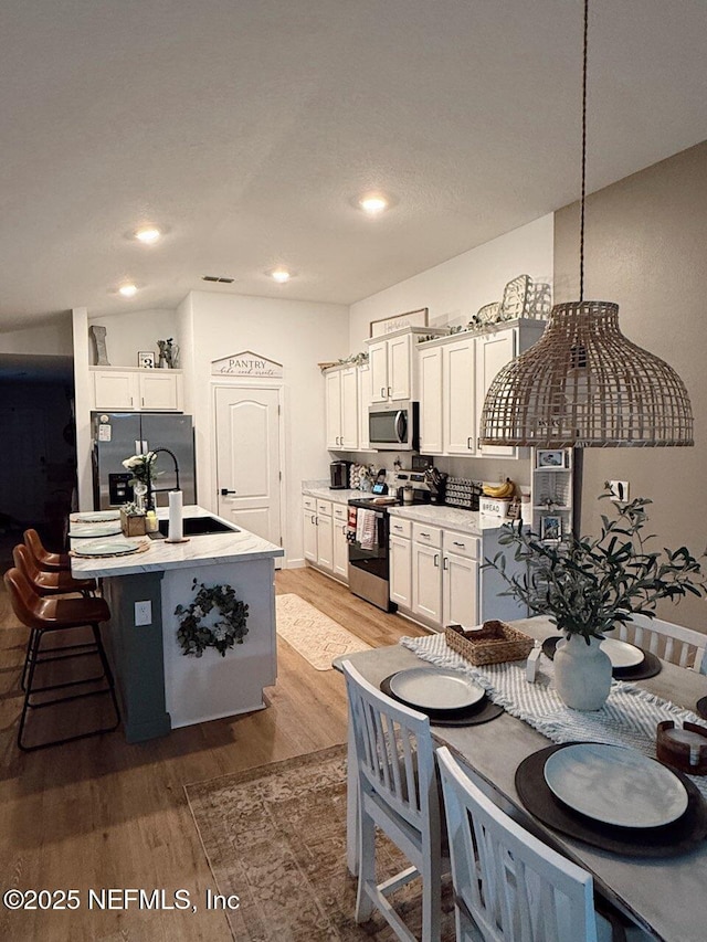 kitchen featuring light countertops, white cabinetry, stainless steel appliances, and light wood-type flooring