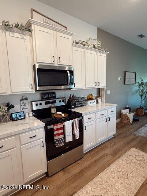 kitchen with white cabinets, stainless steel appliances, and wood finished floors