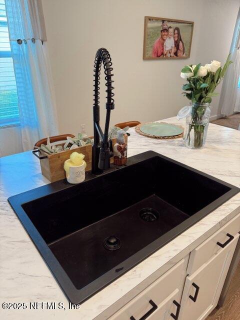 room details with white cabinetry, light countertops, and a sink