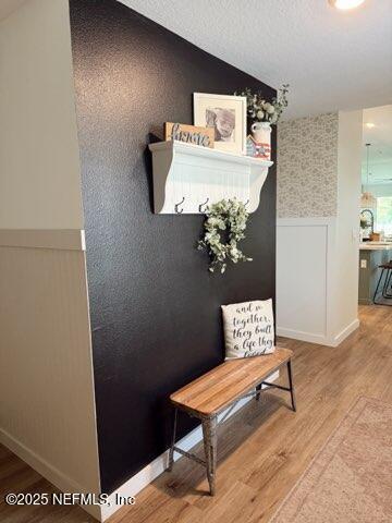 mudroom with wood finished floors, a wainscoted wall, a textured ceiling, and lofted ceiling
