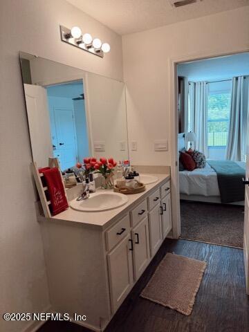 ensuite bathroom with double vanity, wood finished floors, ensuite bathroom, and a sink