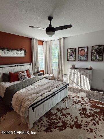 bedroom with a textured ceiling, wood finished floors, and a ceiling fan