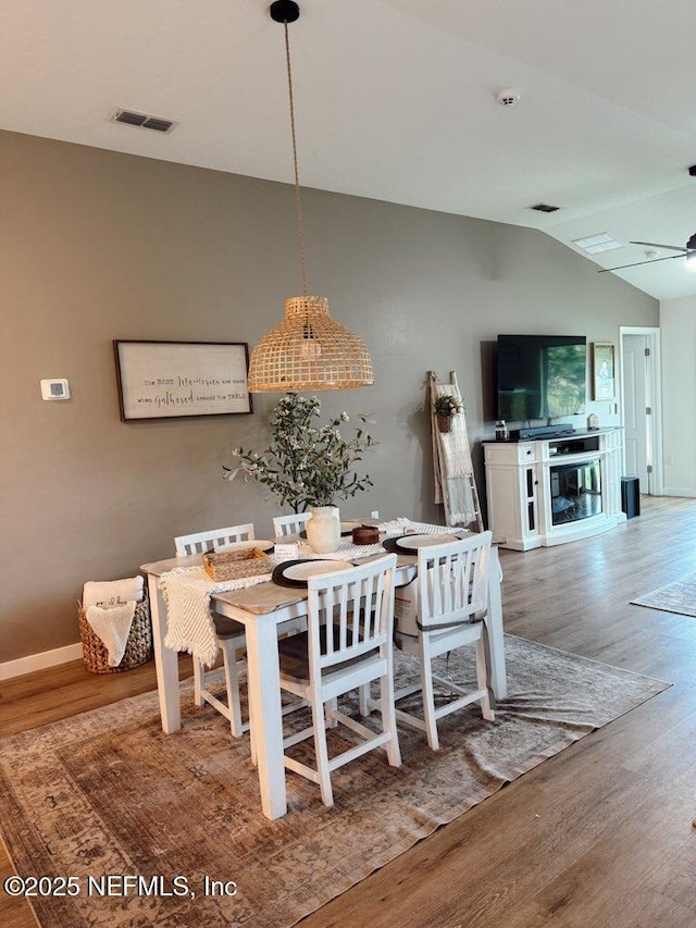 dining room with wood finished floors, ceiling fan, baseboards, visible vents, and lofted ceiling
