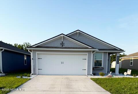 single story home featuring driveway, a front yard, and an attached garage