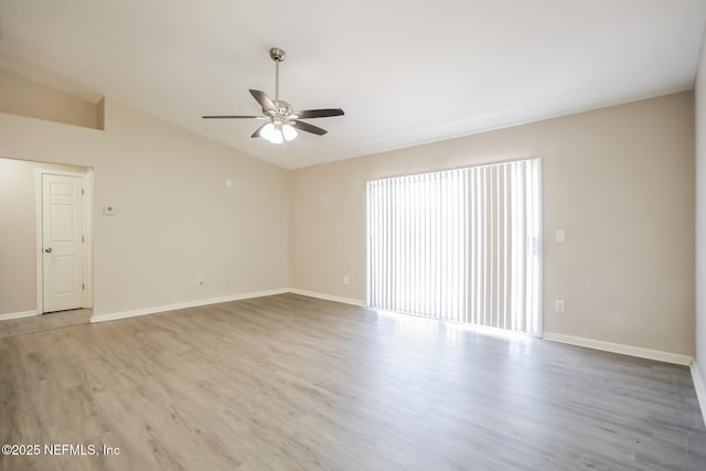 spare room featuring baseboards, wood finished floors, ceiling fan, and lofted ceiling