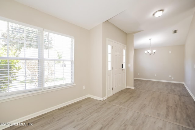foyer entrance featuring baseboards, light wood-style flooring, a chandelier, and a healthy amount of sunlight
