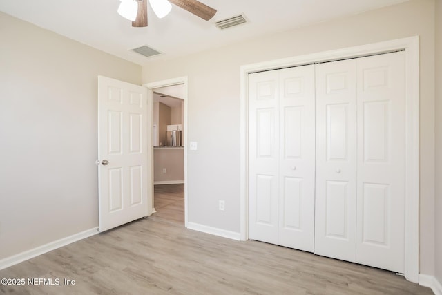 unfurnished bedroom featuring a closet, visible vents, wood finished floors, and baseboards