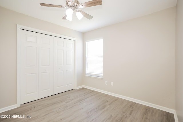 unfurnished bedroom with light wood-type flooring, a closet, a ceiling fan, and baseboards