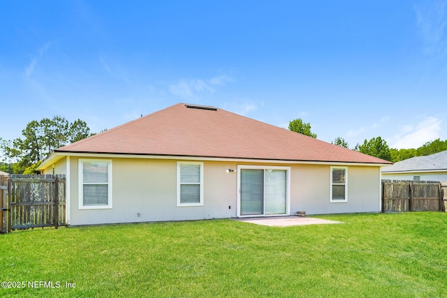 rear view of house with stucco siding, a lawn, a patio, and a fenced backyard