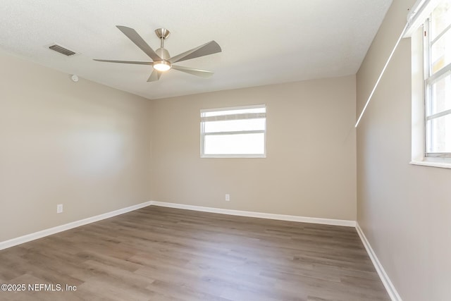 empty room featuring baseboards, visible vents, wood finished floors, and ceiling fan