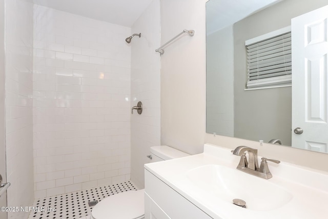 full bathroom featuring toilet, a tile shower, and vanity