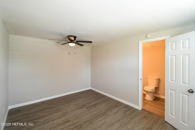unfurnished bedroom featuring ensuite bath, ceiling fan, wood finished floors, and baseboards