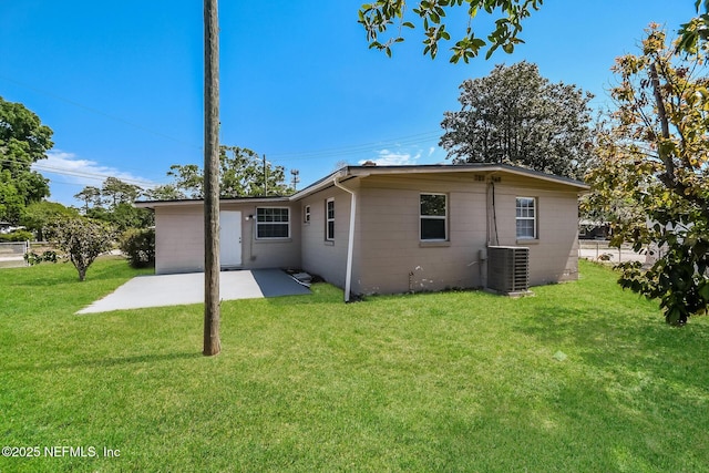 back of house with a patio, a yard, central AC, and concrete block siding