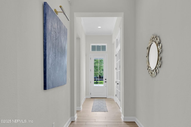 doorway with visible vents, ornamental molding, baseboards, and wood finished floors