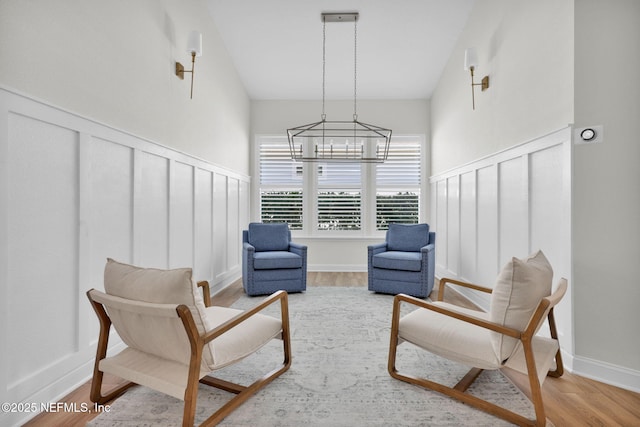sitting room with baseboards, wood finished floors, and a chandelier