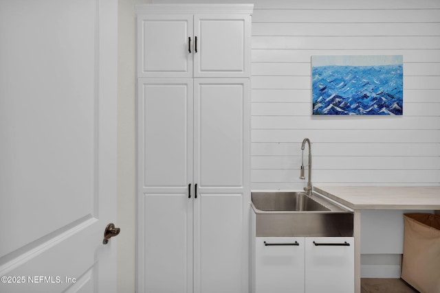 kitchen featuring white cabinets, a sink, and light countertops