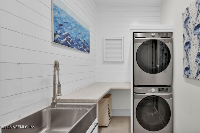 laundry room with laundry area, a sink, stacked washing maching and dryer, wood walls, and light tile patterned floors