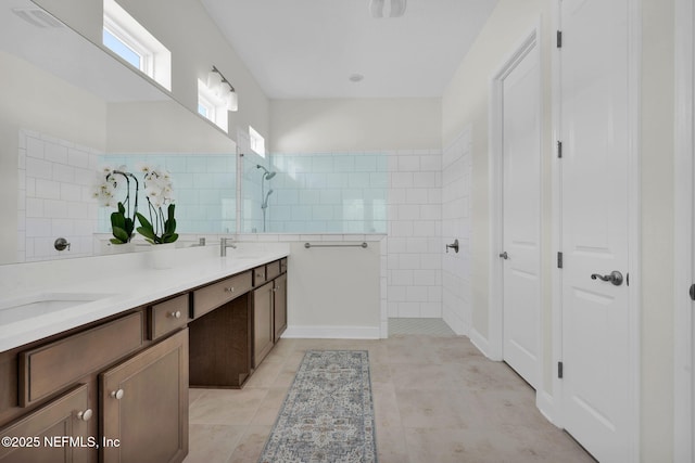 full bathroom featuring double vanity, a sink, a walk in shower, and tile walls