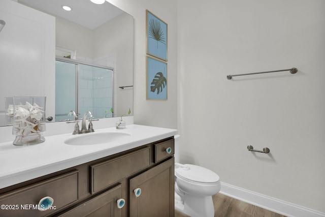 full bath featuring vanity, toilet, baseboards, wood finished floors, and a stall shower