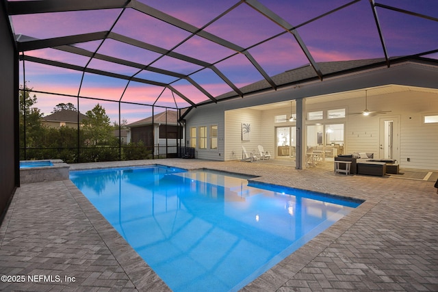 view of pool with ceiling fan, a lanai, a pool with connected hot tub, a patio, and outdoor lounge area