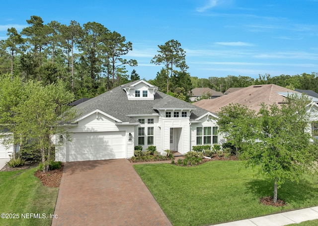 view of front of home featuring a front yard, decorative driveway, an attached garage, and roof with shingles
