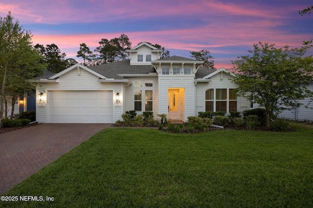 traditional-style house with decorative driveway, a shingled roof, a front lawn, and a garage