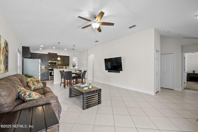living room with a ceiling fan, visible vents, arched walkways, light tile patterned floors, and lofted ceiling