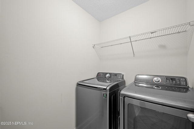 clothes washing area with independent washer and dryer, a textured ceiling, and laundry area