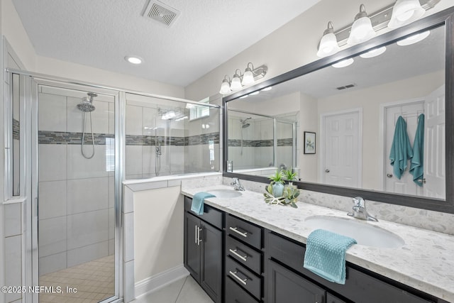 full bathroom featuring visible vents, a sink, a stall shower, and double vanity
