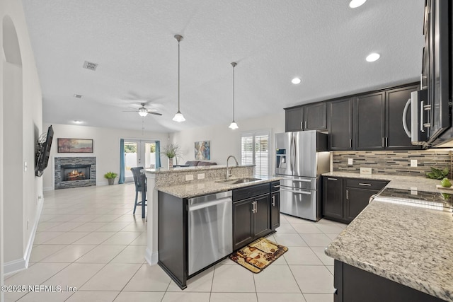 kitchen with visible vents, decorative backsplash, open floor plan, a sink, and appliances with stainless steel finishes