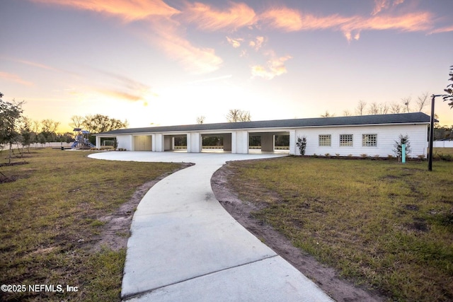 view of front facade with a front lawn, playground community, and concrete driveway