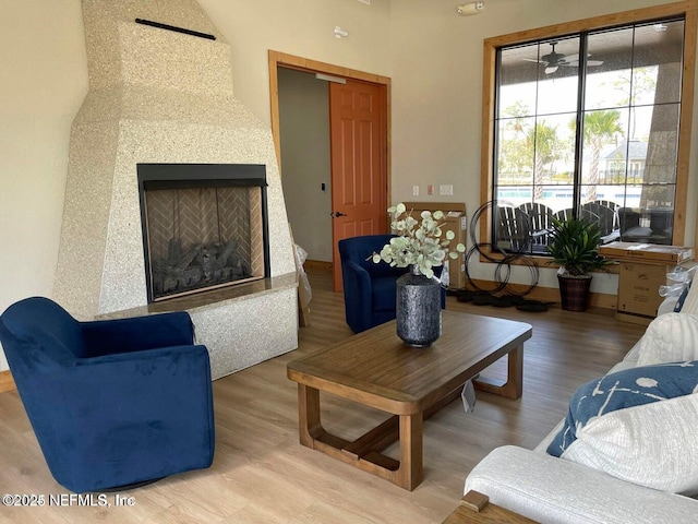living room with a fireplace with raised hearth and wood finished floors