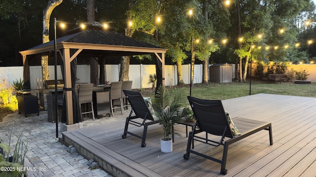 wooden deck with an outdoor structure, a lawn, a fenced backyard, a storage unit, and a gazebo