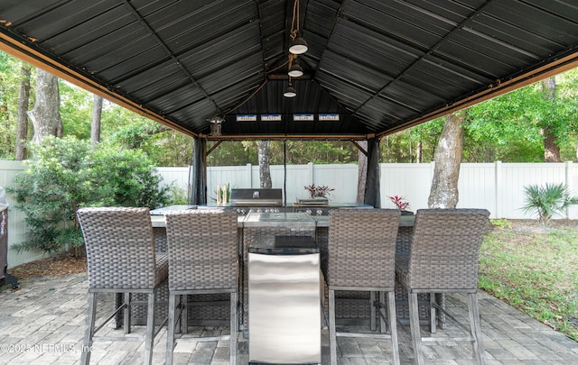view of patio with a fenced backyard, an outdoor kitchen, area for grilling, a gazebo, and outdoor dining space