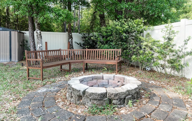 view of yard with an outdoor structure, a fenced backyard, a fire pit, and a storage shed