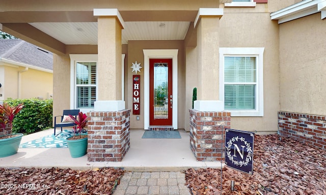 view of exterior entry featuring stucco siding and a porch