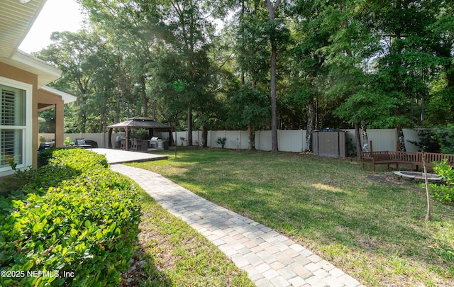 view of yard with a gazebo, a fenced backyard, a storage shed, and a patio
