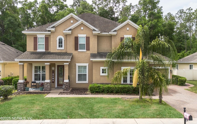 view of front facade featuring a porch, fence, a front lawn, a shingled roof, and stucco siding