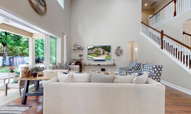 living area featuring a towering ceiling, plenty of natural light, arched walkways, and visible vents