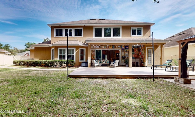 back of property with a lawn, a wooden deck, fence, outdoor lounge area, and stucco siding