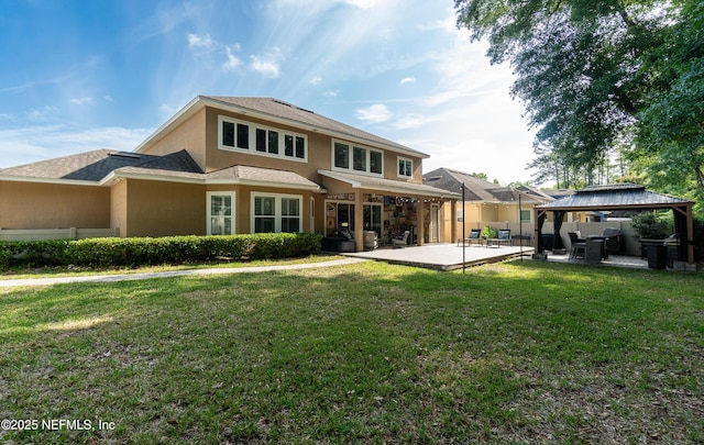 rear view of property with roof with shingles, a lawn, a gazebo, a patio, and stucco siding