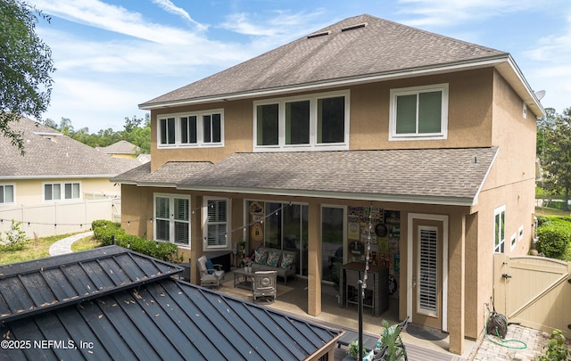 back of property with a shingled roof, stucco siding, a gate, and fence
