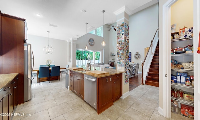 kitchen featuring a sink, light tile patterned floors, hanging light fixtures, and stainless steel appliances