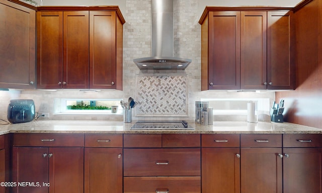 kitchen featuring black electric cooktop, light stone countertops, decorative backsplash, and wall chimney exhaust hood