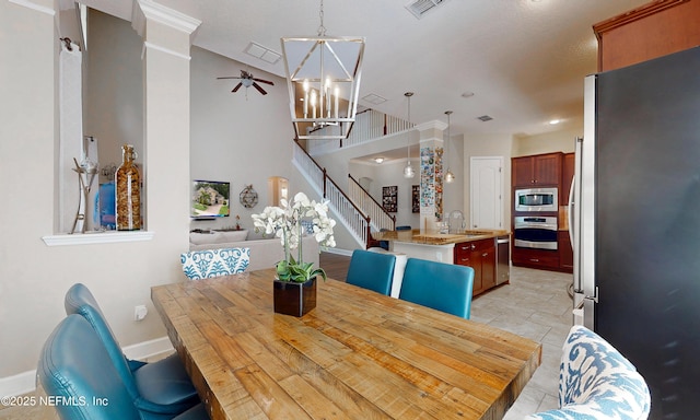 dining room featuring visible vents, stairs, ceiling fan with notable chandelier, and baseboards