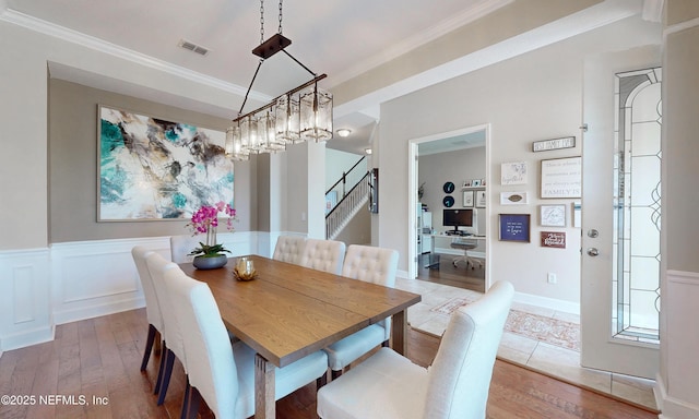 dining space featuring ornamental molding, wood-type flooring, stairs, and visible vents