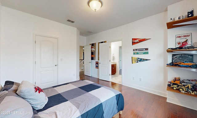 bedroom featuring visible vents, connected bathroom, baseboards, and wood finished floors